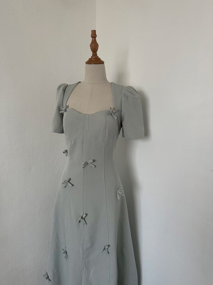 Padded Coquette Dress (Category: Dresses) located in Cabuyao City. Submitted by alycarrou11 (Listing ID 1469631754, Image 2). Description: - Color & Pattern: Sage green with all-over tiny bows - Neckline & Sleeves: Square neckline with short puff sleeves - Design: Fitted bodice with structured front corset seams and a mid-length flared skirt - Material: Smooth fabric - Condition: Clean piece, worn once for a short event.