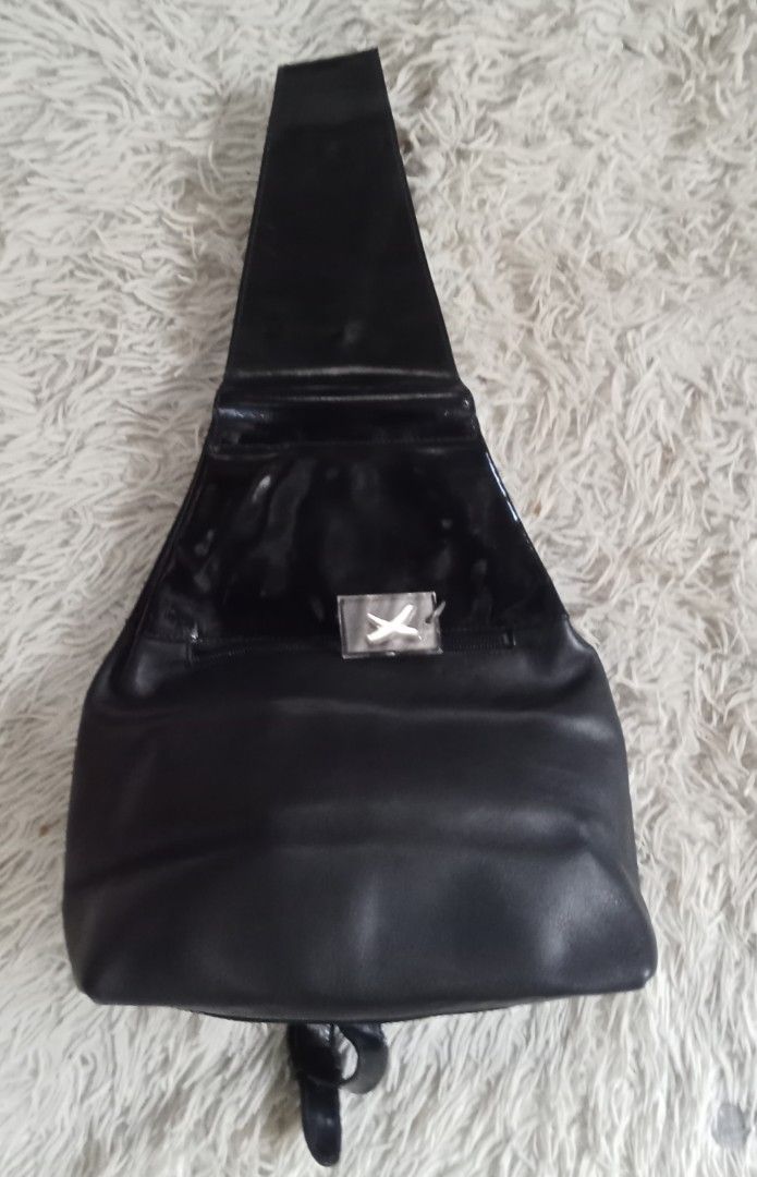 Paloma Picasso Black Leather Backpack Sling Bag (Category: Backpacks) located in Caloocan City. Submitted by noy5o1a (Listing ID 1469637076, Image 1). Description: - Brand: Paloma Picasso - Material: Combination of matte leather and glossy patent sections - Hardware: Distinctive silver-tone X emblem and interior metal plaque - Closure: Secure zip closure for the main compartment - Straps: Adjustable strap configuration - Design: Embossed signatur