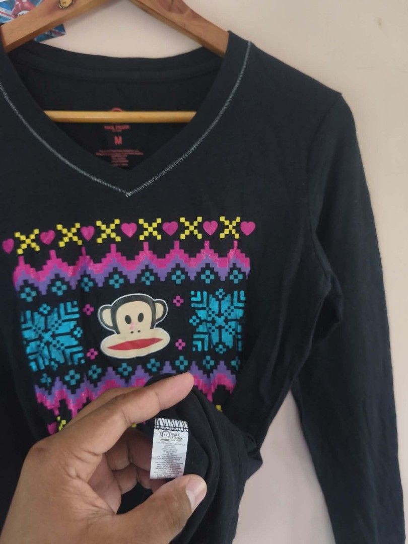 Paul Frank Black Long Sleeve (Category: Longsleeves) located in Manila. Submitted by cookthrift (Listing ID 1469576009, Image 2). Description: - Brand: Paul Frank - Style: Black long sleeve V-neck shirt with contrast stitching - Design: Iconic Julius the Monkey face graphic with colorful winter patterns (snowflakes, hearts, zig-zags) - Size: Medium (M) - Material: Comfortable cotton blend - Condition: Pre-loved, well-maintained - Perfect for casu