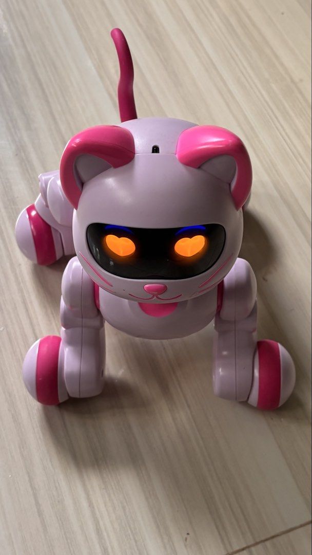 Pink Electronic Robot Cat Toy with Heart Eyes (Category: Interactive Toys) located in La Trinidad. Submitted by caicai1926 (Listing ID 1469619084, Image 2). Description: - Adorable interactive robotic cat toy in pastel purple and bright pink - Features glowing heart-shaped eyes and an upright tail - Movable legs and stands on four fun wheels - Reacts and lights up for endless play - Tested and 100% working great.