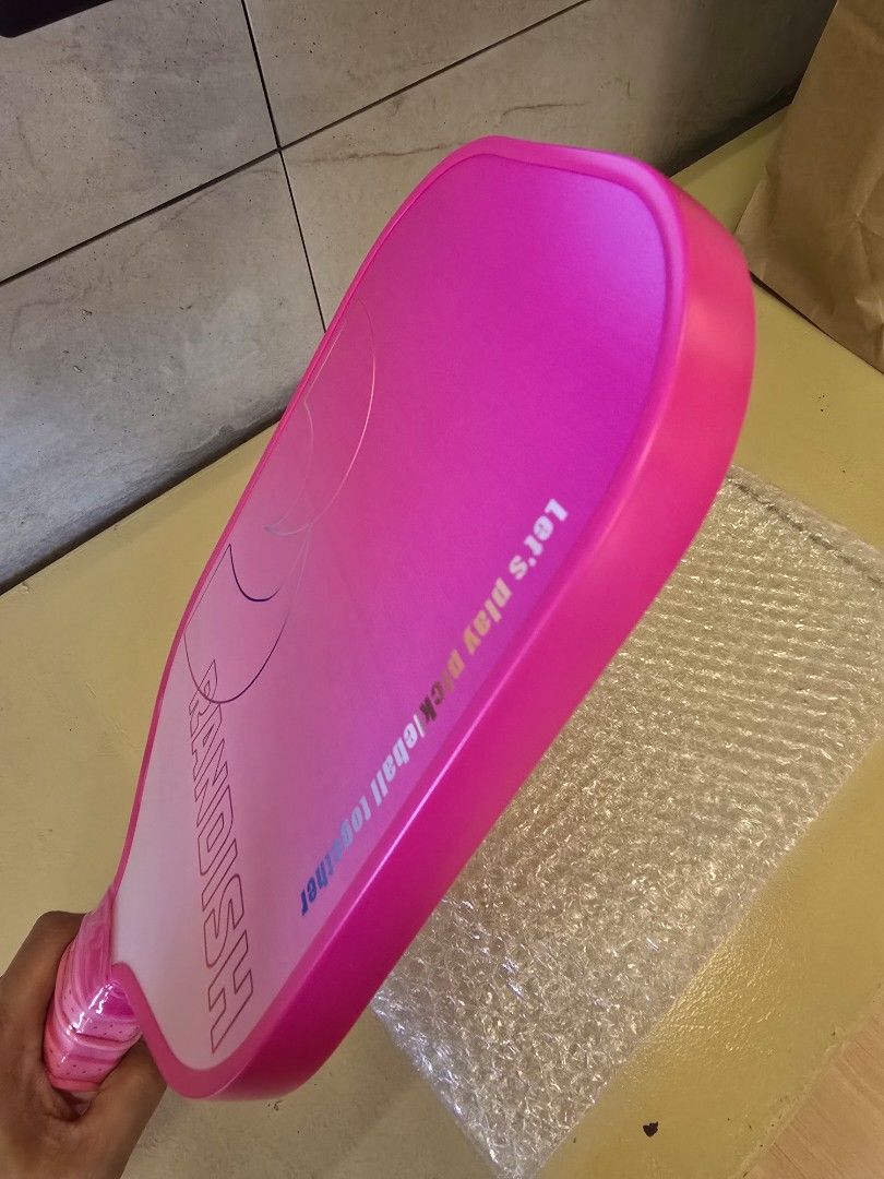 Pink Pickleball Paddle with Wrapped Handle (Category: Racket and Ball Sports) located in Quezon City. Submitted by b.caster (Listing ID 1469595726, Image 3). Description: - 16 mm thick - BRAND NEW - Brand: RANDISH - Design: Pink and white gradient with slogan text - Handle: Perforated pink grip tape wrapped securely (still in protective plastic) - Weight: Lightweight - Condition: Brand new, ready for play.