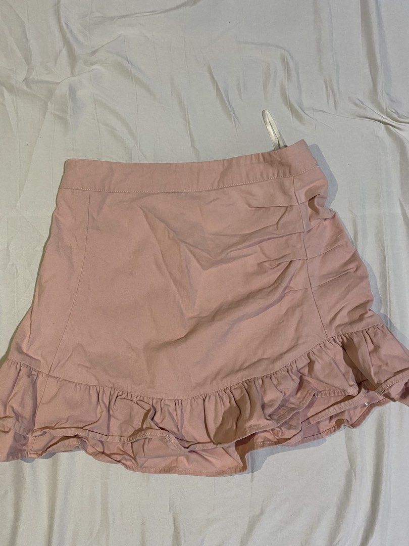 Pink Ruffle Mini Skirt (Category: Skirts) located in Bulacan. Submitted by nonu_sells (Listing ID 1469672606, Image 1). Description: - Color: Light pink - Style: High-waisted mini skirt with front ruched detailing - Design: Playful ruffle hem for added flair - Versatility: Pairs easily with casual tees or blouses, perfect for various outings - Condition: Brand new / Excellent.