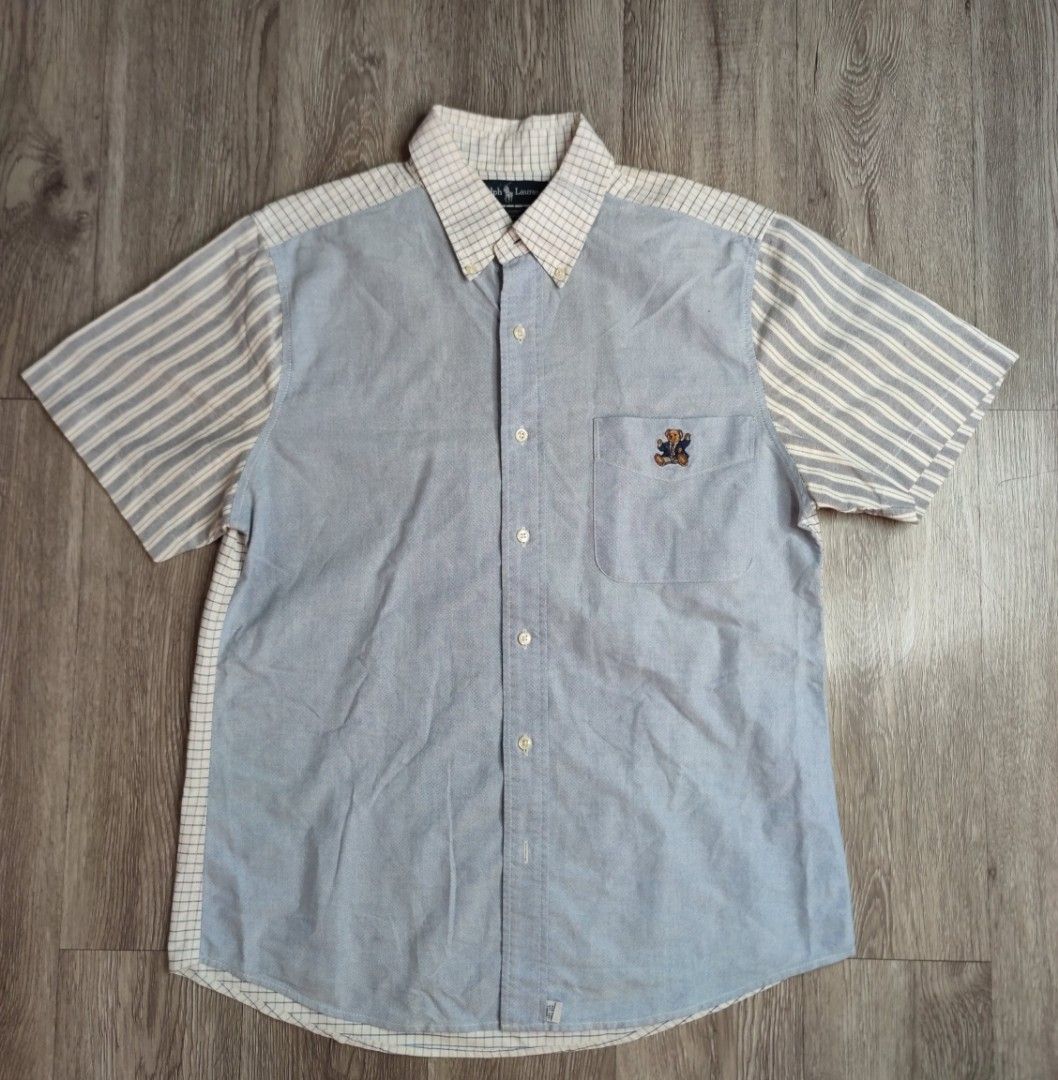 Polo Ralph Lauren Patchwork Bear Short Sleeve Shirt (Category: Tshirts & Polo Shirts ) located in Pasig City. Submitted by vintage.thrifttph (Listing ID 1469652969, Image 1). Description: - Brand: Polo Ralph Lauren - Style: Short sleeve button-down with a unique patchwork design - Details: Blue textured body, striped sleeves, checkered collar and shoulder panel - Accent: Embroidered Polo Bear logo on the chest pocket - Condition: Clean fabric wit
