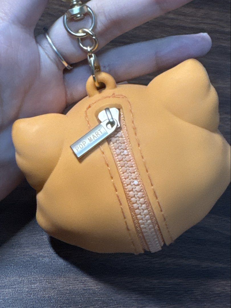 Pop Mart Dimoo World Fox Plush Pendant Keychain (Category: Plushies & Soft Toys) located in Makati City. Submitted by khyfra25 (Listing ID 1469630418, Image 2). Description: - Authentic Pop Mart Dimoo World character in an adorable orange fox hood - Features a functional zipper pocket on the back with a POP MART branded pull tab - Equipped with a sturdy gold-toned clasp keychain for easy bag attachment - Detailed with embossed POP MART and DIMOO 