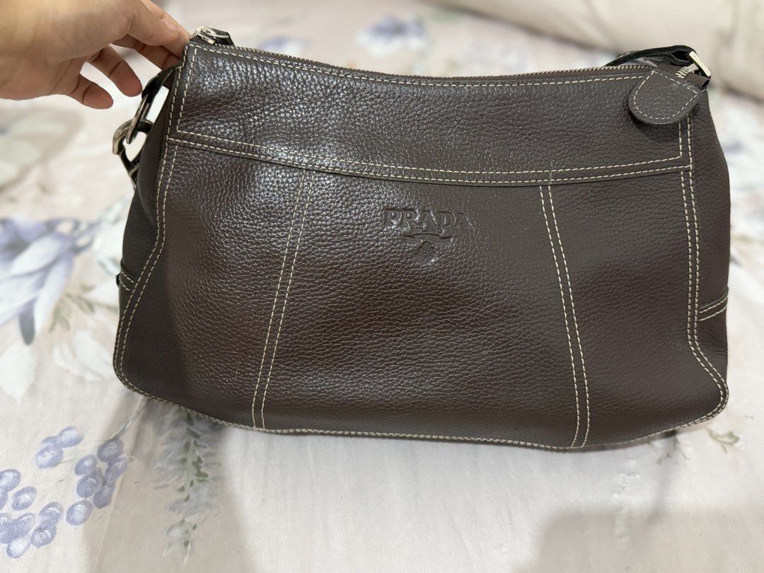 Prada Brown Leather Shoulder Bag (Category: Luxury Bags & Wallets) located in Manila. Submitted by maambeeeeyah (Listing ID 1469676974, Image 1). Description: - Prada shoulder bag in brown pebbled leather - Chic contrast white stitching and embossed front logo - Secure main zippered compartment and exterior back zip pocket - Single adjustable strap with silver-tone hardware and metal clips - Clean bottom and beautifully maintained structured shap