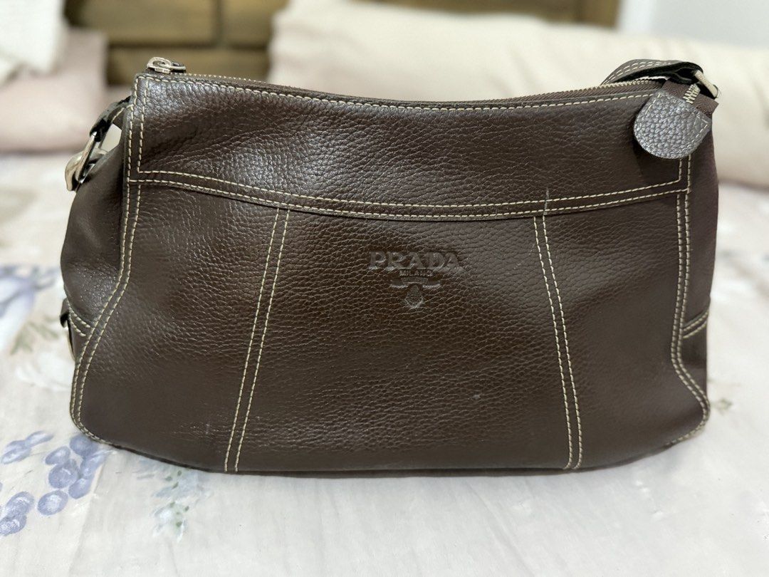 Prada Brown Leather Shoulder Bag (Category: Luxury Bags & Wallets) located in Manila. Submitted by maambeeeeyah (Listing ID 1469676974, Image 2). Description: - Prada shoulder bag in brown pebbled leather - Chic contrast white stitching and embossed front logo - Secure main zippered compartment and exterior back zip pocket - Single adjustable strap with silver-tone hardware and metal clips - Clean bottom and beautifully maintained structured shap