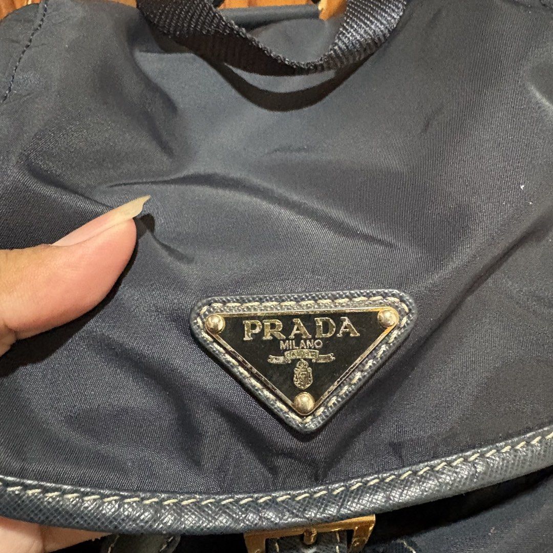 Prada nylon backpack in black (Category: Backpacks) located in Carmen. Submitted by rr_thrifts (Listing ID 1469688793, Image 3). Description: - Brand: Prada - Material: Durable classic black nylon with gold-tone hardware - Design: Iconic triangle logo plaque on the front flap - Closure: Secure drawstring with buckle closure - Pockets: Two convenient front zipped utility pockets - Straps: Adjustable shoulder straps for a comfortable fit - Conditio