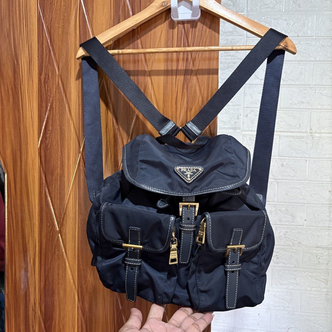 Prada nylon backpack in black (Category: Backpacks) located in Carmen. Submitted by rr_thrifts (Listing ID 1469688793, Image 1). Description: - Brand: Prada - Material: Durable classic black nylon with gold-tone hardware - Design: Iconic triangle logo plaque on the front flap - Closure: Secure drawstring with buckle closure - Pockets: Two convenient front zipped utility pockets - Straps: Adjustable shoulder straps for a comfortable fit - Conditio