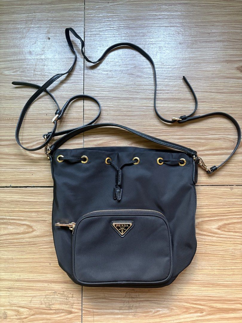 Prada Nylon Bucket Bag (Category: Luxury Bags & Wallets) located in Manila. Submitted by bravestone14 (Listing ID 1469688787, Image 1). Description: Prada nylon bucket bag (Authentic) featuring a drawstring top, gold-tone hardware, and an enameled triangular Prada logo plaque on a front exterior pocket No issue Good as new condition 10k+sf HEARING OFFERS✨ 📩 .