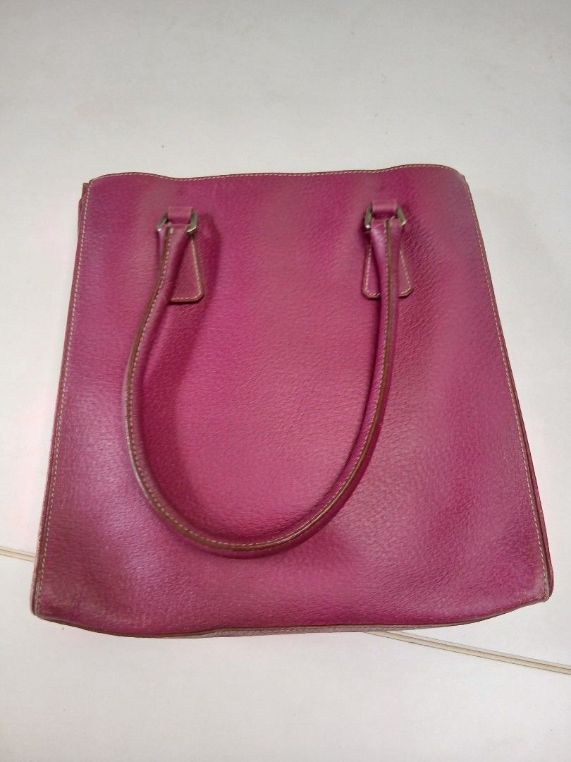 Prada pink leather tote handbag (Category: Luxury Bags & Wallets) located in Cainta. Submitted by chickennuggirl (Listing ID 1469635309, Image 3). Description: - Authentic Prada pink leather tote bag - Dual shoulder straps with adjustable silver hardware buckles - Iconic signature triangular Prada logo plaque on the front - Secure zippered top closure - Contrast green fabric interior with Prada jacquard pattern - Includes interior metal brand pla