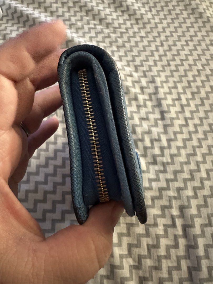 Prada Saffiano Blue Leather Wallet (Category: Luxury Bags & Wallets) located in Antipolo. Submitted by prelovedcloseta (Listing ID 1469608186, Image 2). Description: - Authentic blue Prada Saffiano leather wallet - Elegant gold hardware logo on the front - Secure snap closure strap - Multiple card slots and spacious cash sections - Convenient zippered side pocket for coins - Compact size fits easily into any everyday bag.