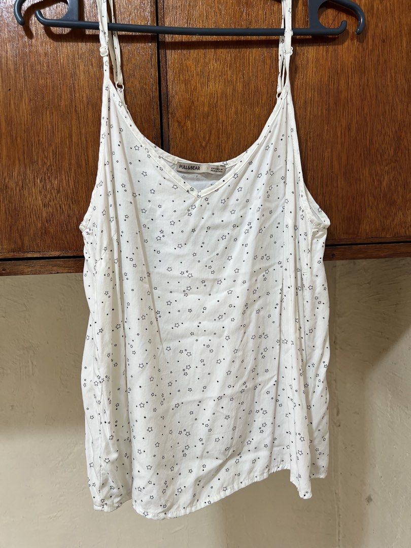 Pull&Bear White Star Print Camisole Tank Top Size S (Category: Sleeveless) located in Makati City. Submitted by sheenaxxxx (Listing ID 1469606635, Image 1). Description: - Brand: Pull&Bear - Size: S - Color/Pattern: White with all-over black star print - Design: V-neckline with adjustable spaghetti straps - Material: Lightweight and breezy fabric - Origin: Made in China - Condition/Use: Great warm-weather staple or layering piece.