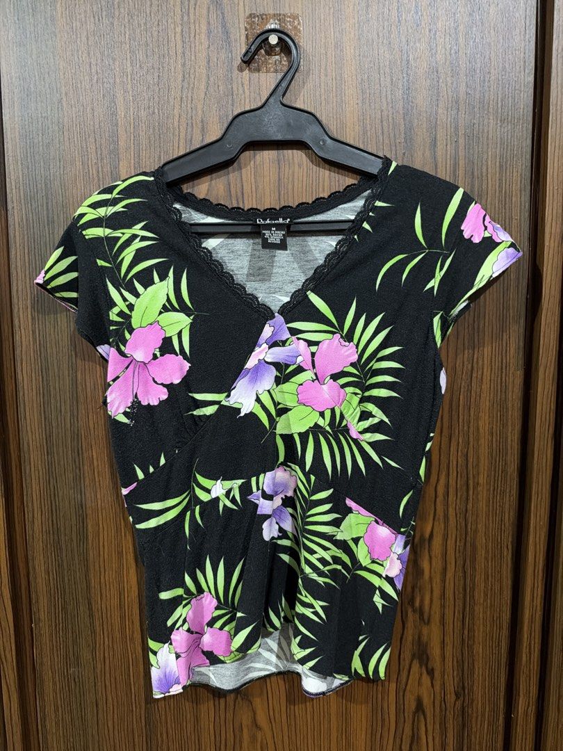 Rafaella Black Floral V-Neck Top Size M (Category: Blouses) located in Quezon City. Submitted by co.coph (Listing ID 1469700689, Image 1). Description: - Brand: Rafaella - Size: M (tag attached) - Color/Design: Black with vibrant green and purple tropical floral print - Neckline: Crossover V-neck with delicate black lace trim - Sleeves: Short sleeves - Material: 95% rayon, 5% spandex (soft, stretchy, and comfortable for daily wear) - Origin: Made