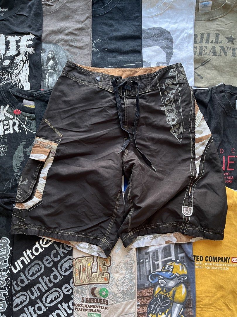 Redsand Brown Camo Cargo Board Shorts (Category: Shorts) located in Baao. Submitted by plainclothesdept (Listing ID 1469696910, Image 1). Description: y2k redsand boardshorts waist - 28-30 in. length - 20 in. hem - 11 in. no flaws - Brand: Redsand - Color: Dark brown with camo side panels - Features: Cargo pocket, drawstring waist, white contrast stitching, and small branding patch - Fit: Relaxed fit - Ideal for: Surfing, skating, or casual beach