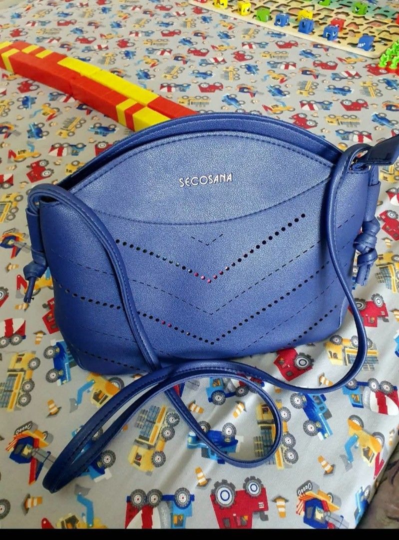 Secosana blue crossbody handbag (Category: Cross-body Bags) located in Marilao. Submitted by joycehart (Listing ID 1469612208, Image 1). Description: - Brand: Secosana - Color: Blue - Material: Clean faux leather - Style: Structured dome shape crossbody bag with zip top closure - Features: Metal brand logo and stylish perforated chevron patterns - Strap: Thin, adjustable shoulder strap - Capacity: Great everyday size for phone, keys, and wallet.