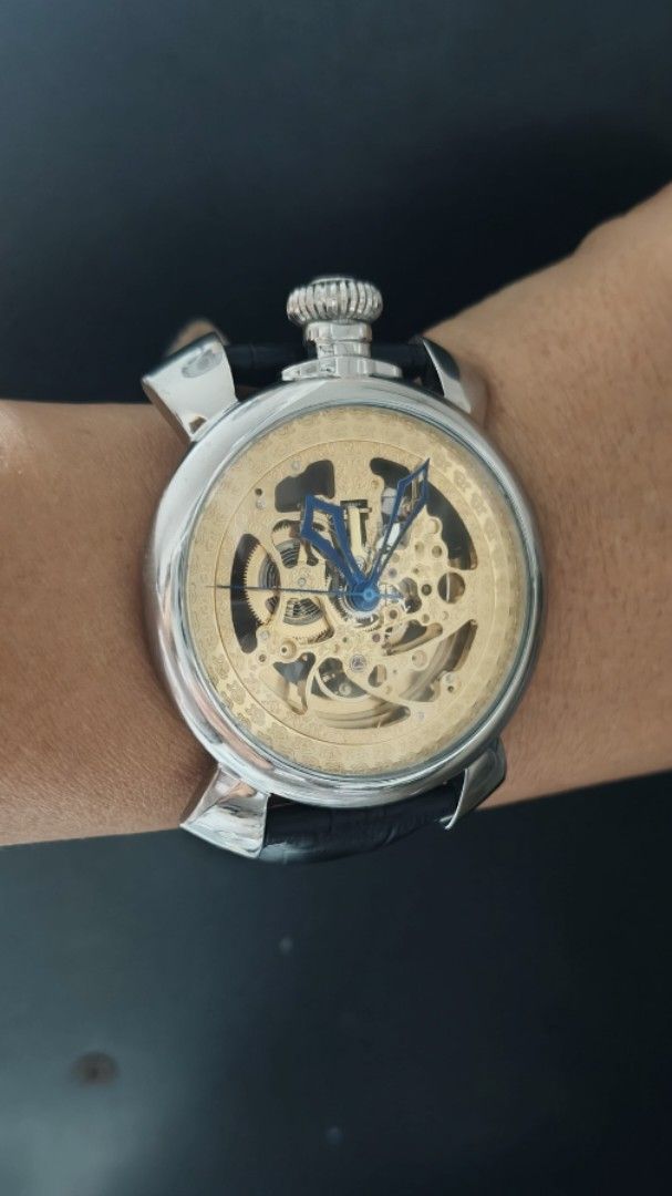 Skeleton Mechanical Wristwatch Gold Dial Blue Hands Leather Strap (Category: Men's Watches) located in Taguig. Submitted by mercyeugen28914 (Listing ID 1469723689, Image 1). Description: - Stunning gold skeleton mechanical watch with visible gears on the dial and caseback - Eye-catching blue hands set against a metallic gold movement plate - Silver-tone round case featuring a unique top-positioned large crown - Premium black leather strap with a 