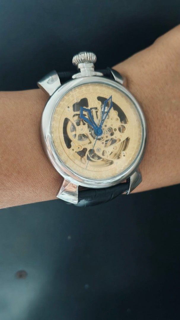 Skeleton Mechanical Wristwatch Gold Dial Blue Hands Leather Strap (Category: Men's Watches) located in Taguig. Submitted by mercyeugen28914 (Listing ID 1469723689, Image 3). Description: - Stunning gold skeleton mechanical watch with visible gears on the dial and caseback - Eye-catching blue hands set against a metallic gold movement plate - Silver-tone round case featuring a unique top-positioned large crown - Premium black leather strap with a 