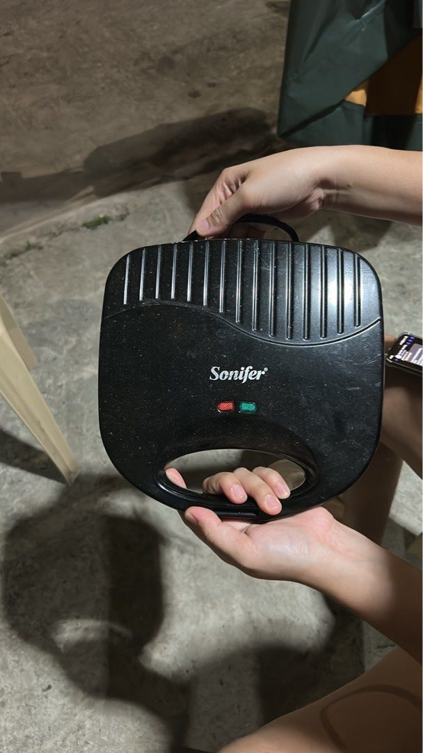 Sonifer black waffle maker (Category: Cookware & Accessories) located in Cavite. Submitted by jm_gutierrez (Listing ID 1469604705, Image 1). Description: - Brand/Model: Sonifer Black Waffle Maker - Condition: Works great, ready to use - Plates: Non-stick interior for easy cleaning - Features: Indicator lights on top - Design: Compact size, perfect for small kitchens and easy storage - Ideal for: Quick and easy breakfast snacks.