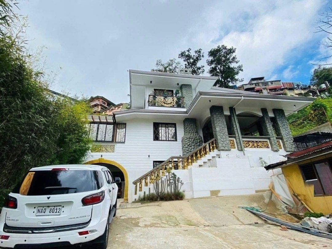 Spacious Multi-Storey Residential House (Category: Construction & Building Materials) located in Baguio. Submitted by markmartin3 (Listing ID 1469621178, Image 3). Description: - Multi-storey residential house with a striking white facade and stone pillars - Dedicated car parking space included - Bright and airy layout with large windows for natural light - Elegant wooden flooring throughout the home - Luxurious carved golden detailing on doors a