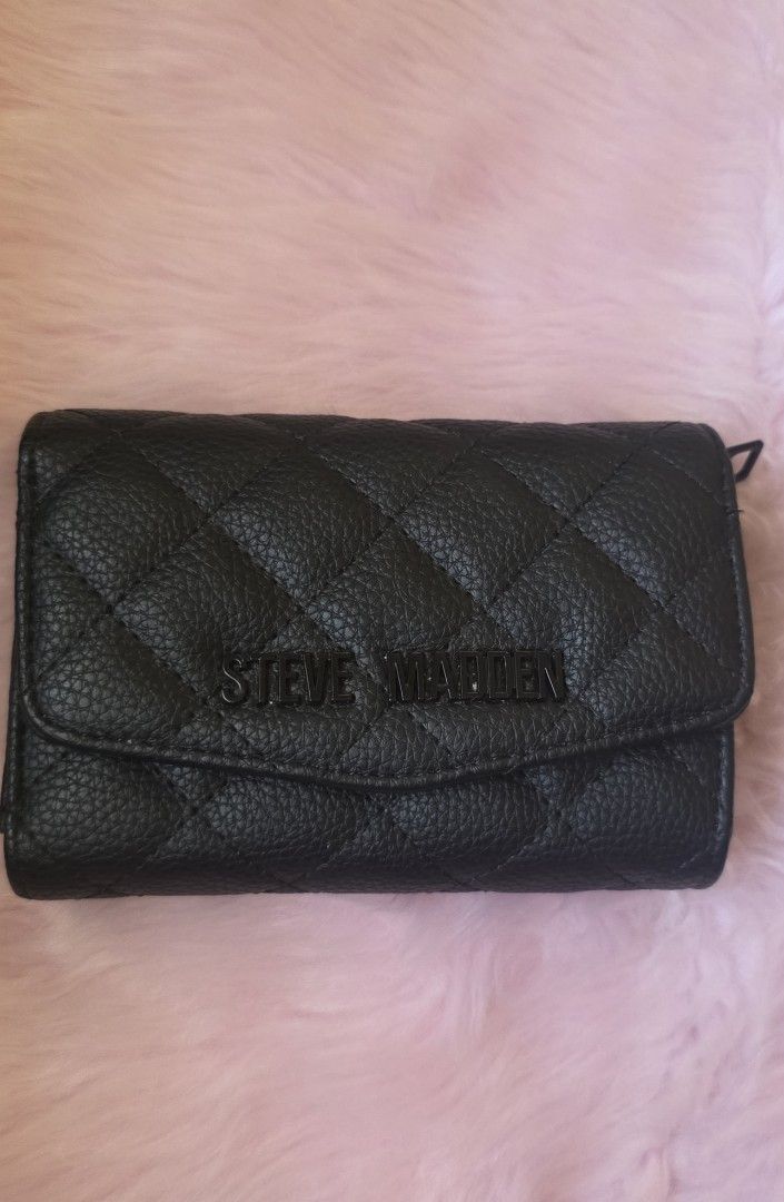 Steve Madden Black Quilted Wallet (Category: Wallets & Card holders) located in Amadeo. Submitted by riccchfinds (Listing ID 1469648107, Image 1). Description: - Brand: Steve Madden - Color: Classic Black with chic quilted texture - Material: Durable pebble-grain synthetic leather - Closure: Fold-over flap with secure magnetic snap button - Interior Features: Multiple card slots, clear ID window, and cash compartments - Condition: Clean inside an