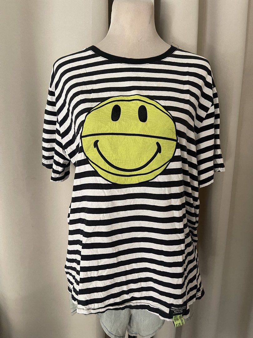Striped embroid smiley (Category: Shirts) located in Cainta. Submitted by zlove111 (Listing ID 1469619528, Image 1). Description: - Style: Casual oversized tee - Design: Classic black and white stripes with a bold neon yellow smiley face graphic - Details: Round collar, short sleeves, and a brand fabric tag near the bottom hem - Fit: Super comfy and relaxed - Condition: Brand new / Excellent quality - Shipping: Ships fast via J&T mop gcsh no issu