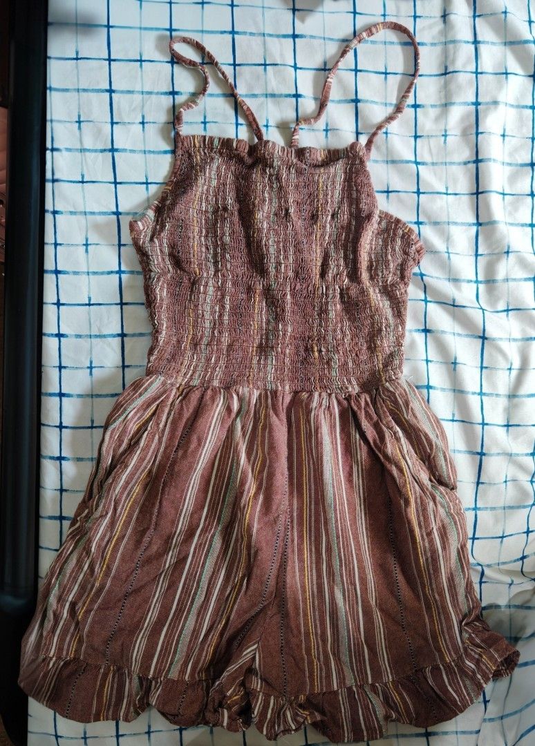 Striped Smocked Romper with Ruffle Hem (Category: Rompers) located in Paranaque City. Submitted by MLandCobyApple (Listing ID 1469626671, Image 1). Description: - Color/Pattern: Brown with white, yellow, and green vertical stripes - Top: Stretchy smocked bodice with crisscross spaghetti straps in the back - Bottom: Shorts with a cute ruffle trim along the hem - Material: Lightweight and breezy fabric, ideal for hot days - Condition: Brand new / E
