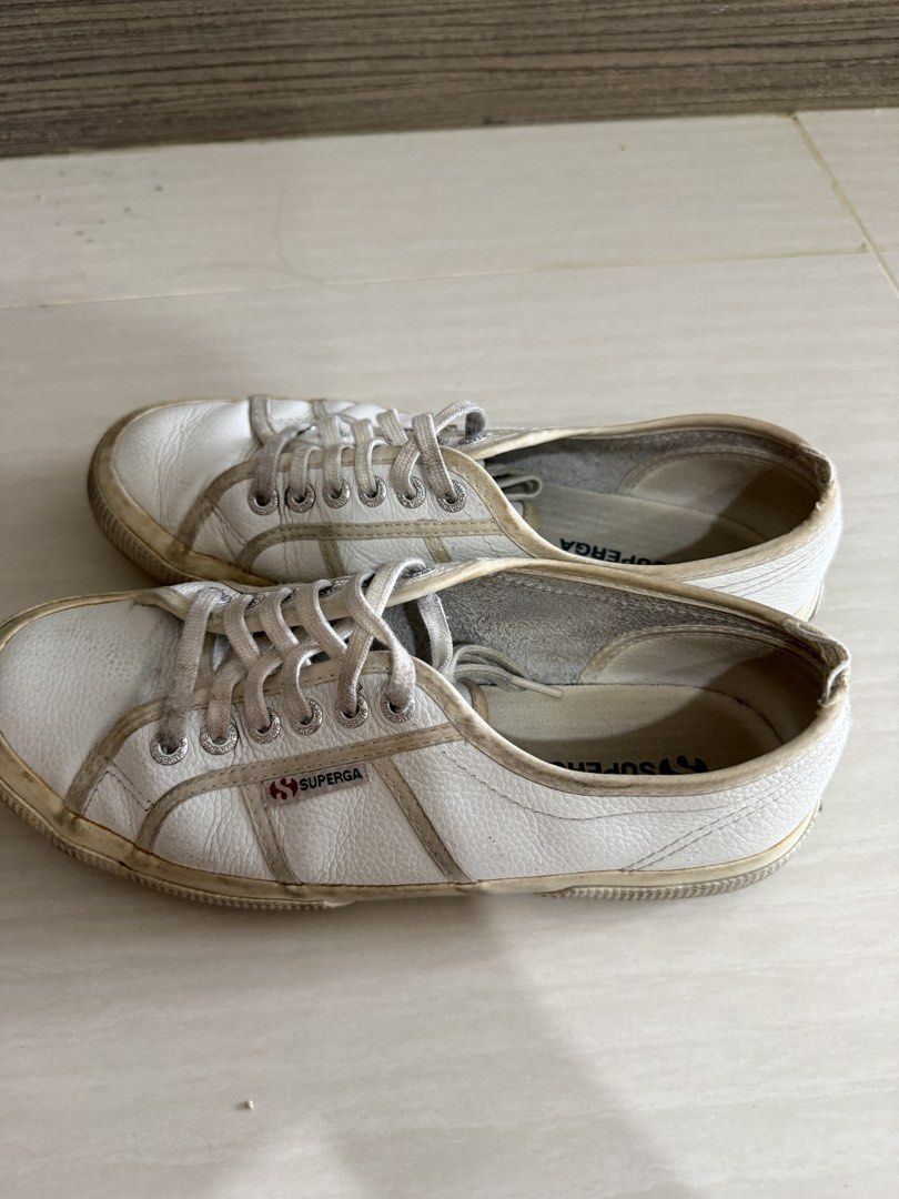 Superga White Leather Sneakers (Category: Sneakers) located in Muntinlupa City. Submitted by golf823 (Listing ID 1469598485, Image 3). Description: White leather Superga sneakers with lace-up closure. Classic low-top design with signature branding on the side and inner sole. Rubber outsoles show normal wear. Upper material has a textured leather finish with visible signs of usage around the edges and rubber trims. Comfortable casual daily shoes..