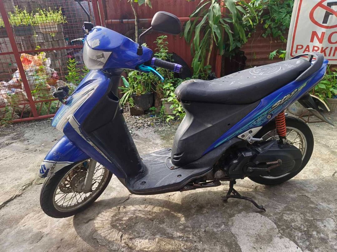Suzuki Step 125 Blue Scooter Motorcycle (Category: Motorbikes for Sale) located in Valenzuela. Submitted by archie.rivera04-40444 (Listing ID 1469590508, Image 3). Description: Suzuki Step 125 automatic scooter, bright blue body panels with white accent graphics. Black vinyl seat. Spoke wheels with front disc brake. Kickstand and center stand installed. Handlebars fitted with custom grips and levers. Standard floorboard and exhaust pipe. Normal w