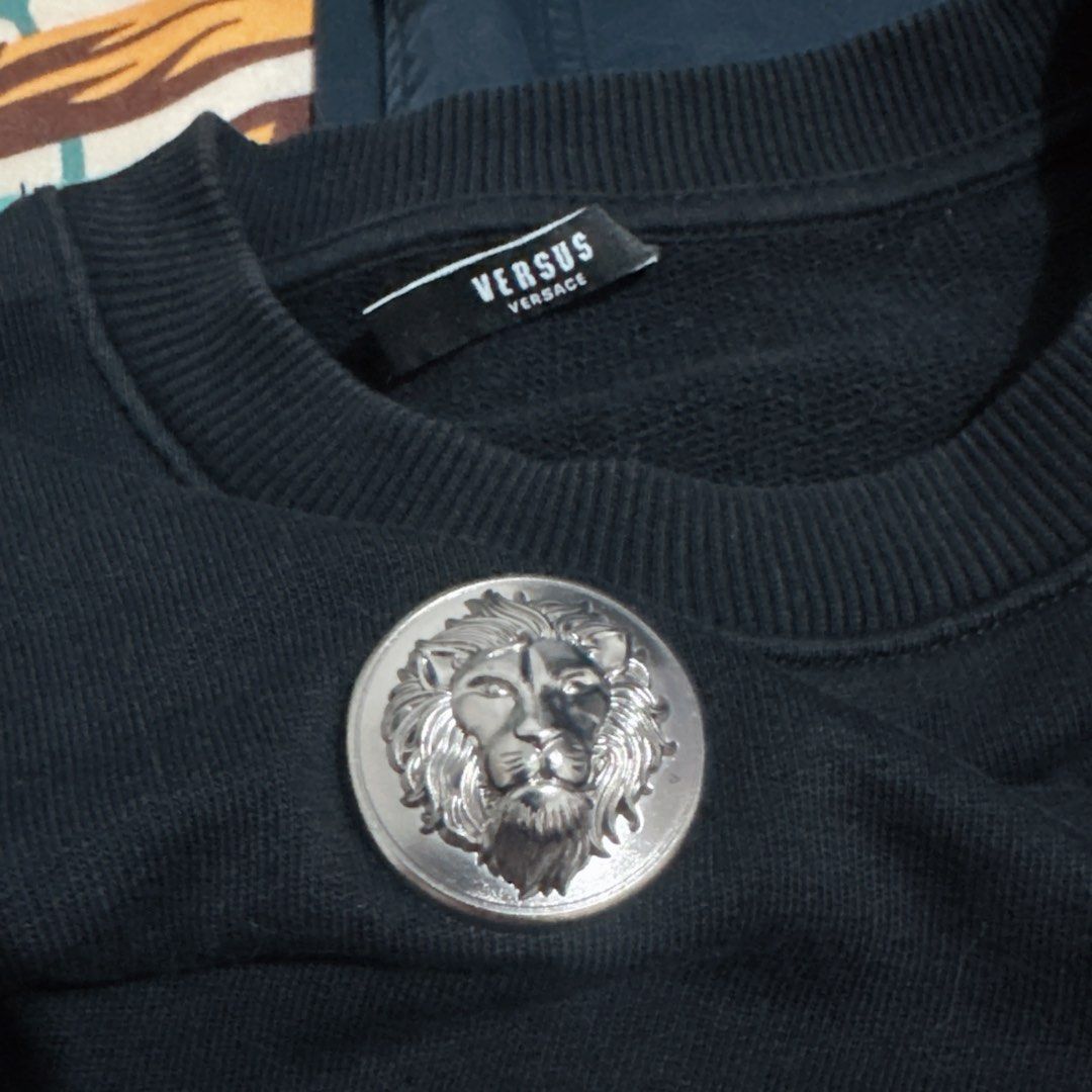 Sweatshirt Versus Versace Black Lion Head Button (Category: Coats, Jackets and Outerwear) located in Manila. Submitted by jeromepsg12 (Listing ID 1469596076, Image 2). Description: - Brand: Versus Versace - Color: Classic Black - Only use 2x - Material: Warm, comfortable cotton blend - Design: Statement streetwear featuring scattered silver-tone lion head metal buttons on the front - Details: Long sleeves with ribbed cuffs and hem, classic label 