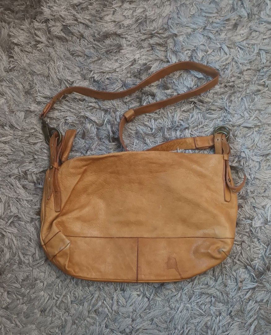 Tan Leather Crossbody Shoulder Bag (Category: Cross-body Bags) located in Mandaluyong City. Submitted by bestill4610 (Listing ID 1469682601, Image 3). Description: Selling for my niece Thrifted here on Carousell Made in Italy Genuine leather Thick yet soft and lightweight!👍 W 16" x H 10" Clean interior. Strap good condition. Issue: Rubbed corners & stain at base, not noticeable since its in the bottom. See last pics.