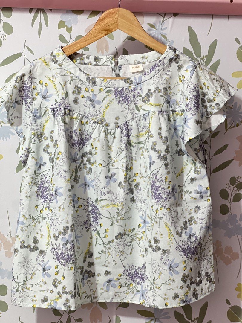 Te chichi Floral Print Blouse Size M (Category: Blouses) located in Pasig City. Submitted by morilove (Listing ID 1469585591, Image 1). Description: - Brand: Te chichi (Japanese Brand) - Style: Floral blouse with short flutter sleeves and round neckline - Color/Pattern: Light blue base with purple and grey floral print - Size: Medium (M) - Material: 100% polyester (lightweight and comfortable) - Features: Back button closure, gathered yoke detail