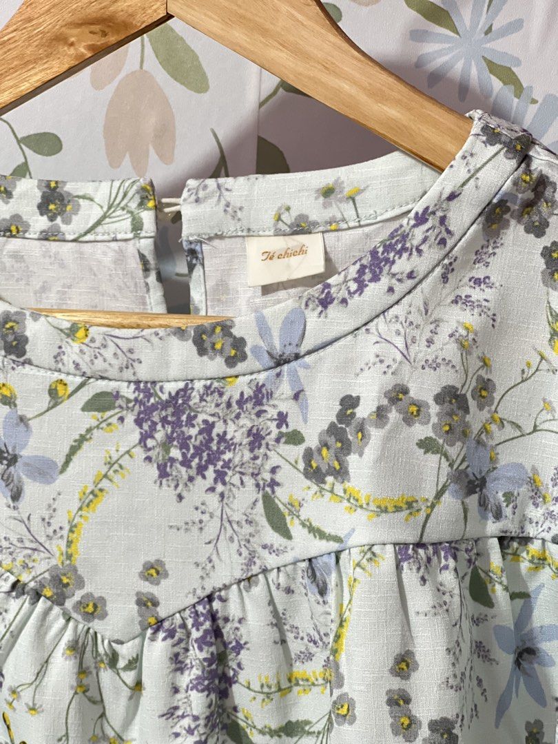 Te chichi Floral Print Blouse Size M (Category: Blouses) located in Pasig City. Submitted by morilove (Listing ID 1469585591, Image 2). Description: - Brand: Te chichi (Japanese Brand) - Style: Floral blouse with short flutter sleeves and round neckline - Color/Pattern: Light blue base with purple and grey floral print - Size: Medium (M) - Material: 100% polyester (lightweight and comfortable) - Features: Back button closure, gathered yoke detail