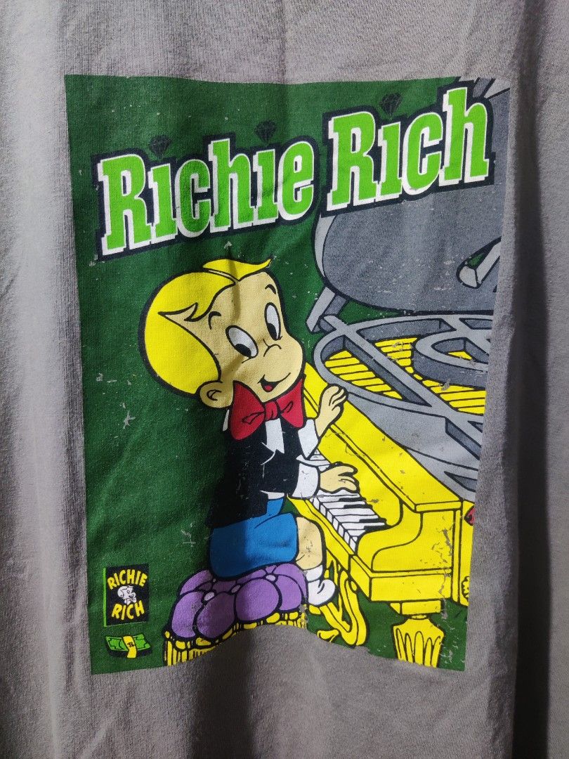Richie Rich Graphic T-Shirt (Category: Tshirts & Polo Shirts ) located in Pasig City. Submitted by shiyenaaa (Listing ID 1469669792, Image 3). Description: - Brand/Collab: Tee Culture x Richie Rich - Color: Grey - Size: 2XL (Relaxed Fit) - Material: 100% Cotton - Design: Large comic graphic on the front, vertical Richie Rich lettering and diamond graphics on the back - Condition: Excellent / As described.