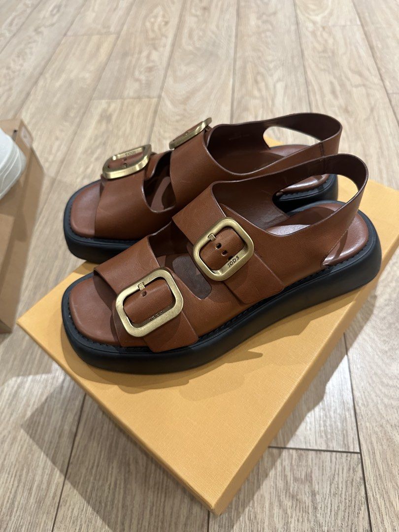 Tod's Leather Buckle Sandals (Category: Flats & Sandals) located in Caloocan City. Submitted by nicsching (Listing ID 1469679992, Image 2). Description: - Brand: Tod's - Style: Two-strap platform sandals with slingback - Color: Brown leather with large gold-tone buckles and thick black soles - Condition: Excellent, premium craftsmanship - Inclusions: Original branded dust bag and orange presentation box - Perfect for: Warm weather, casual outings