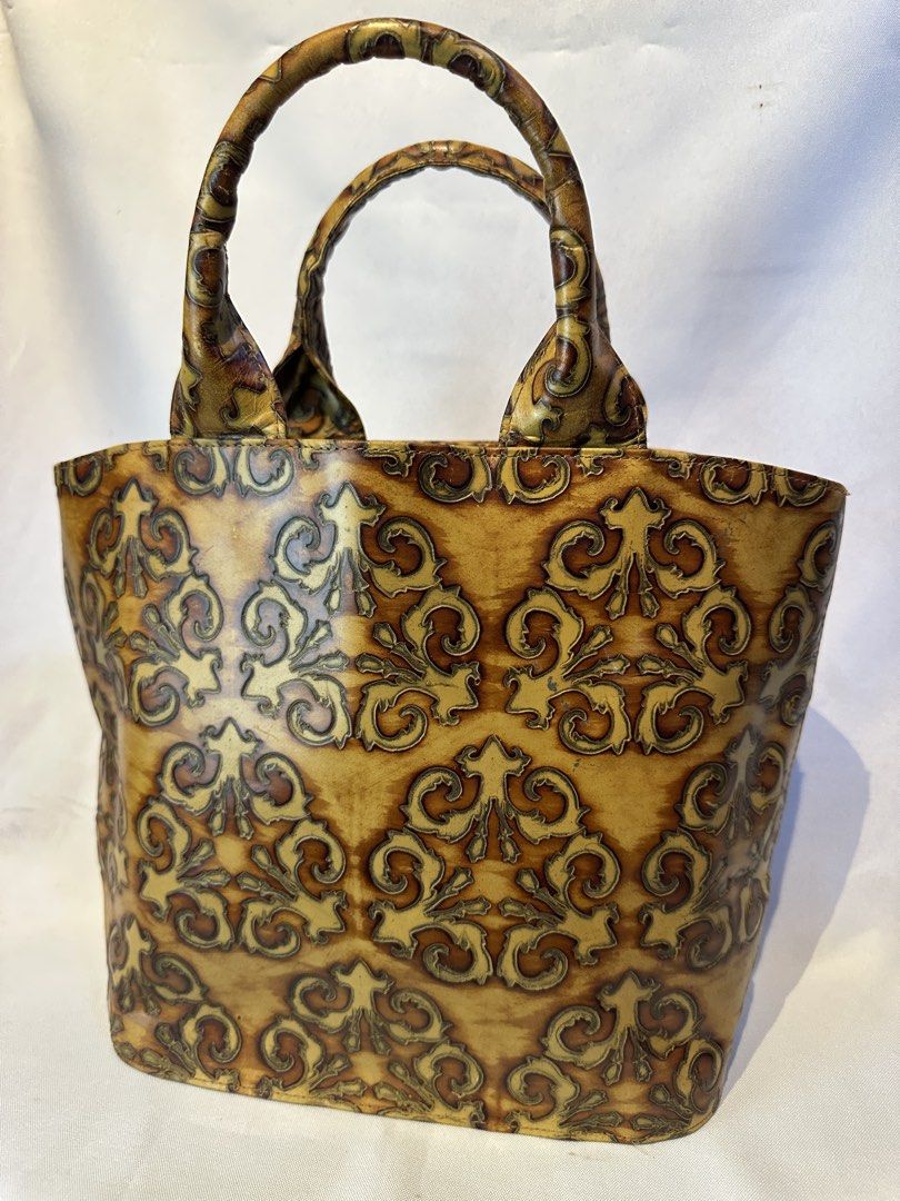 TOOLED Vintage patterned leather tote bag with double handles (Category: Tote Bags) located in Manila. Submitted by originalvintagebagph (Listing ID 1469697019, Image 3). Description: - Elegant brown and gold embossed leather tote with a detailed damask/scroll pattern - Dual rolled leather top handles for comfortable carrying - Clean brown fabric lining with a convenient zipped middle divider compartment - Sturdy structure that holds its shape we