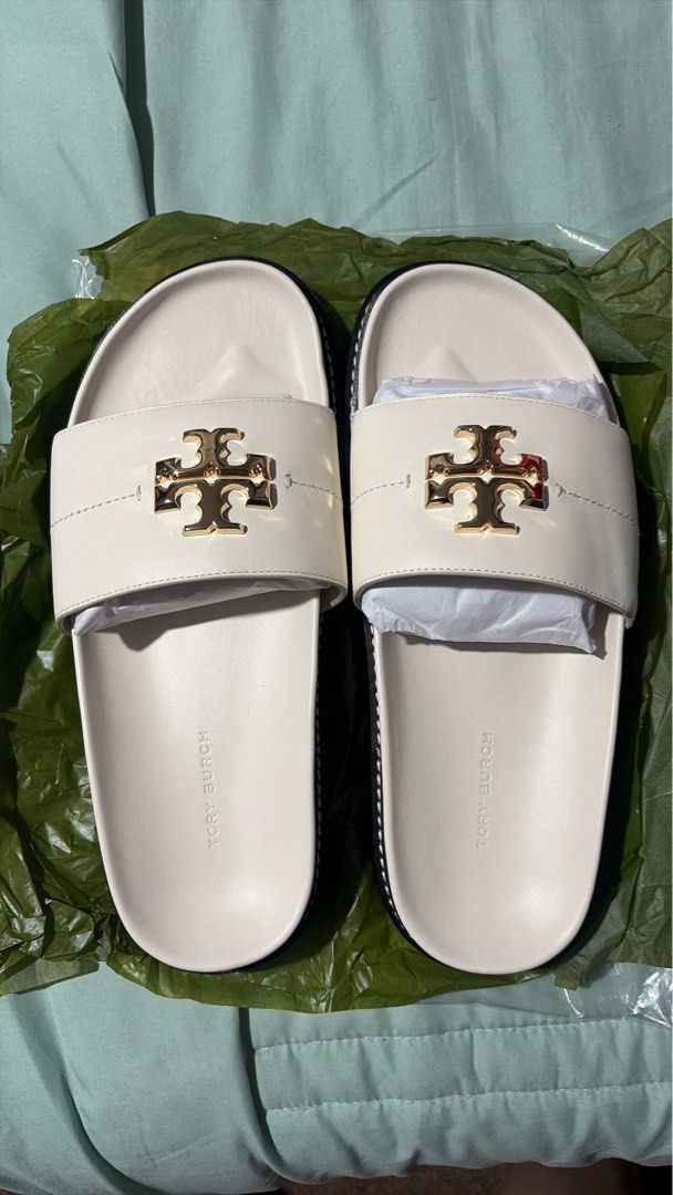 Tory Burch Anatomic Lug Slides (Category: Flats & Sandals) located in Manila. Submitted by libienbien (Listing ID 1469701278, Image 1). Description: - Brand: Tory Burch - Style: White leather slide sandals with gold-tone T logo hardware - Size: US 8 (stamped on sole) - Features: Contoured footbed with molded branding and black ridged rubber outsole - Condition: Includes original paper stuffing inside the straps for shape retention.