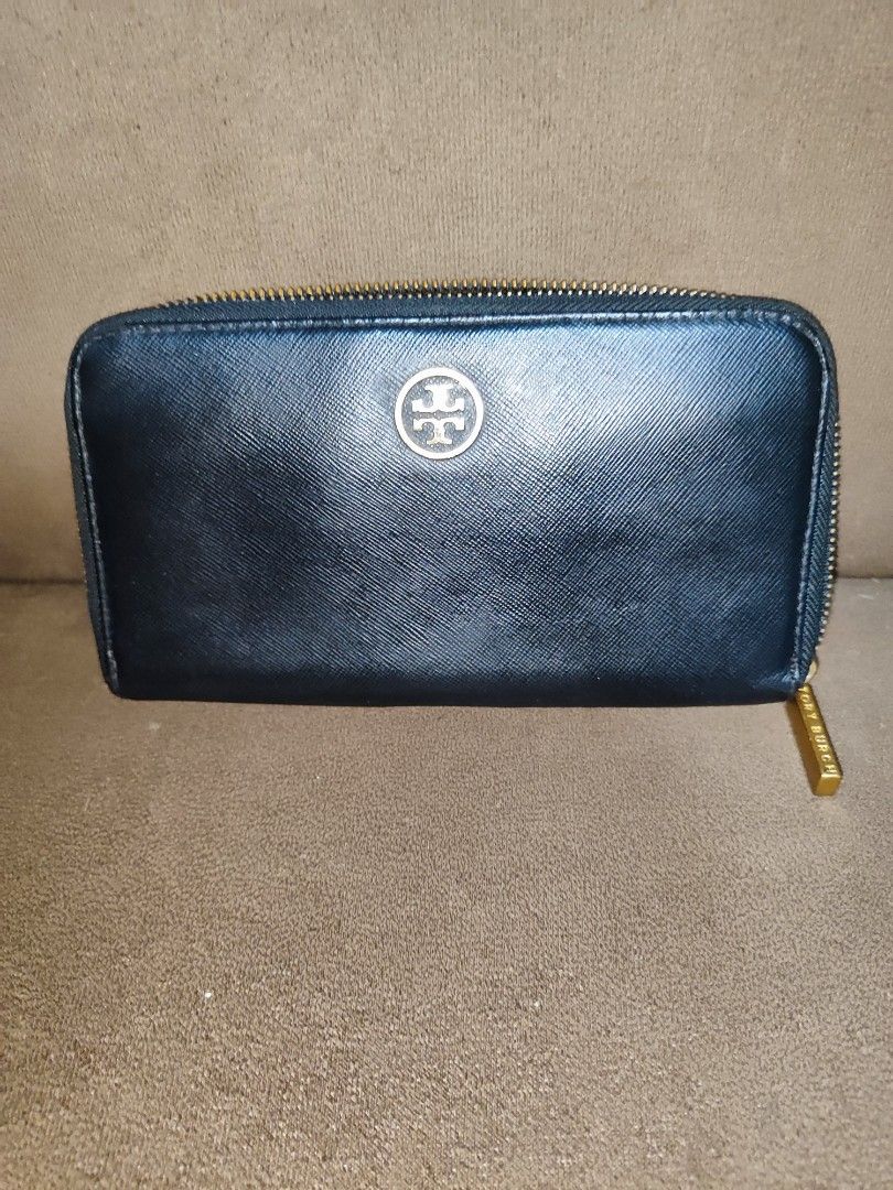 Tory Burch Black Saffiano Leather Zip Around Wallet (Category: Luxury Bags & Wallets) located in Paniqui. Submitted by arlenepari29210 (Listing ID 1469709577, Image 1). Description: - Brand: Tory Burch - Material: Premium black Saffiano leather - Hardware: Elegant gold-tone with iconic front logo emblem - Closure: Smooth zip-around closure - Interior: Multiple card slots, slip compartments, and a central zippered coin pocket - Size: Standard long