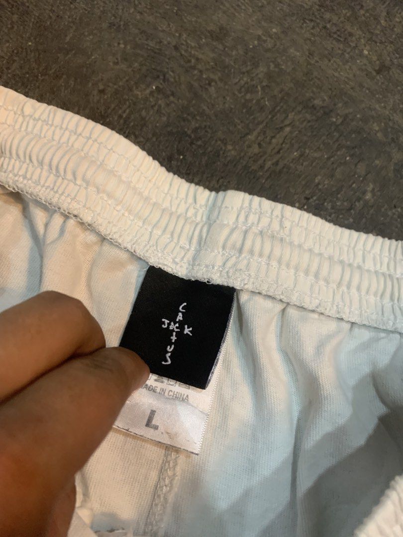 Travis Scott Cactus Jack Graphic Shorts White Size L (Category: Shorts) located in Cagayan de Oro. Submitted by agboysalis60090 (Listing ID 1469709632, Image 2). Description: Travis Scott Cactus Jack white graphic shorts. Drawstring elastic waist with back pocket. Unique abstract prints, red silhouette figure on the front, and large logo graphics on the back legs. Made by Travis Scott, 2022 Laflame Enterprises. 100 percent cotton material, machin