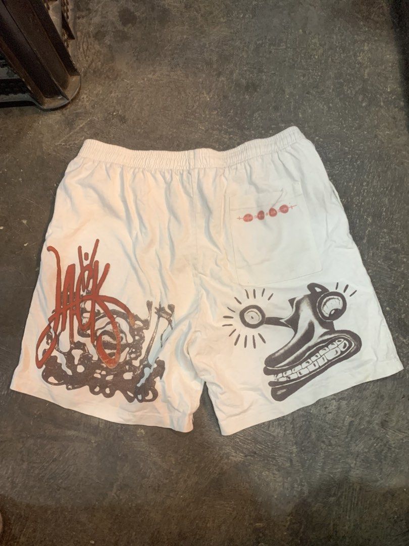 Travis Scott Cactus Jack Graphic Shorts White Size L (Category: Shorts) located in Cagayan de Oro. Submitted by agboysalis60090 (Listing ID 1469709632, Image 3). Description: Travis Scott Cactus Jack white graphic shorts. Drawstring elastic waist with back pocket. Unique abstract prints, red silhouette figure on the front, and large logo graphics on the back legs. Made by Travis Scott, 2022 Laflame Enterprises. 100 percent cotton material, machin