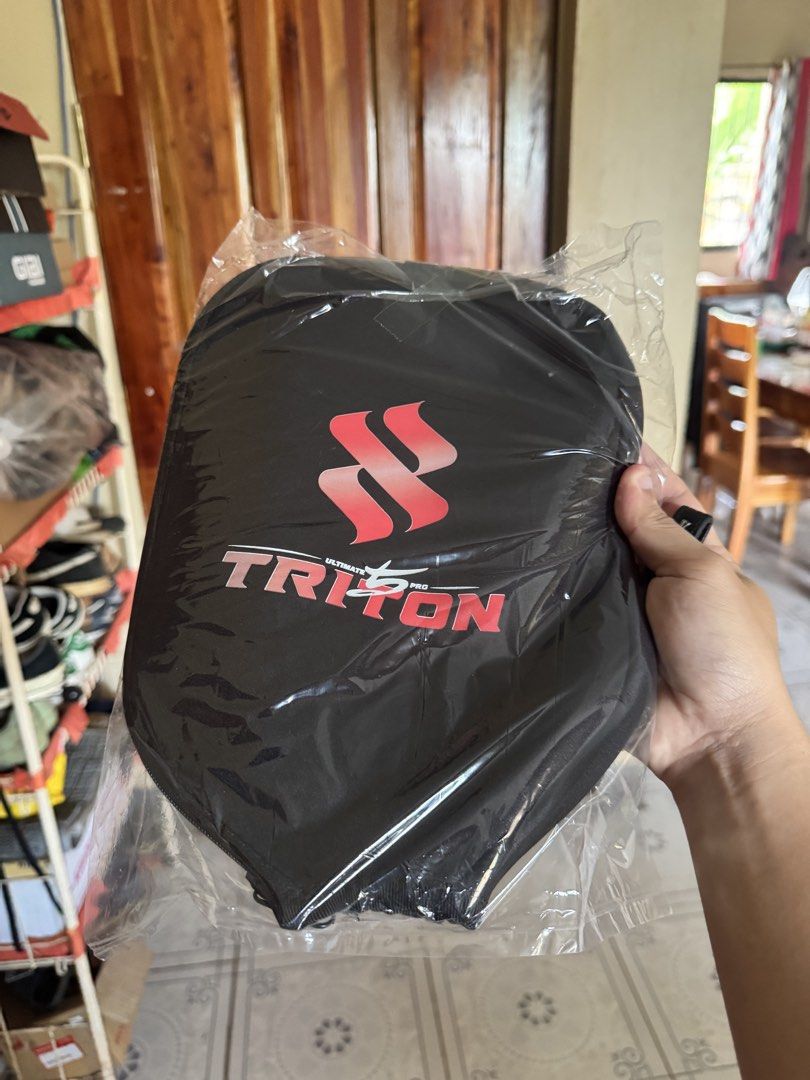 Triton Ultimate Pro Pickleball Paddle Cover (Category: Racket and Ball Sports) located in Pagadian. Submitted by lancism.g (Listing ID 1469644585, Image 1). Description: - Brand: Triton Ultimate Pro - Color: Black - Condition: Brand new, still sealed in original clear plastic packaging - Design: Red logo on one side, white graphic on the reverse - Protection: Keeps your pickleball paddle safe from scratches and duds.