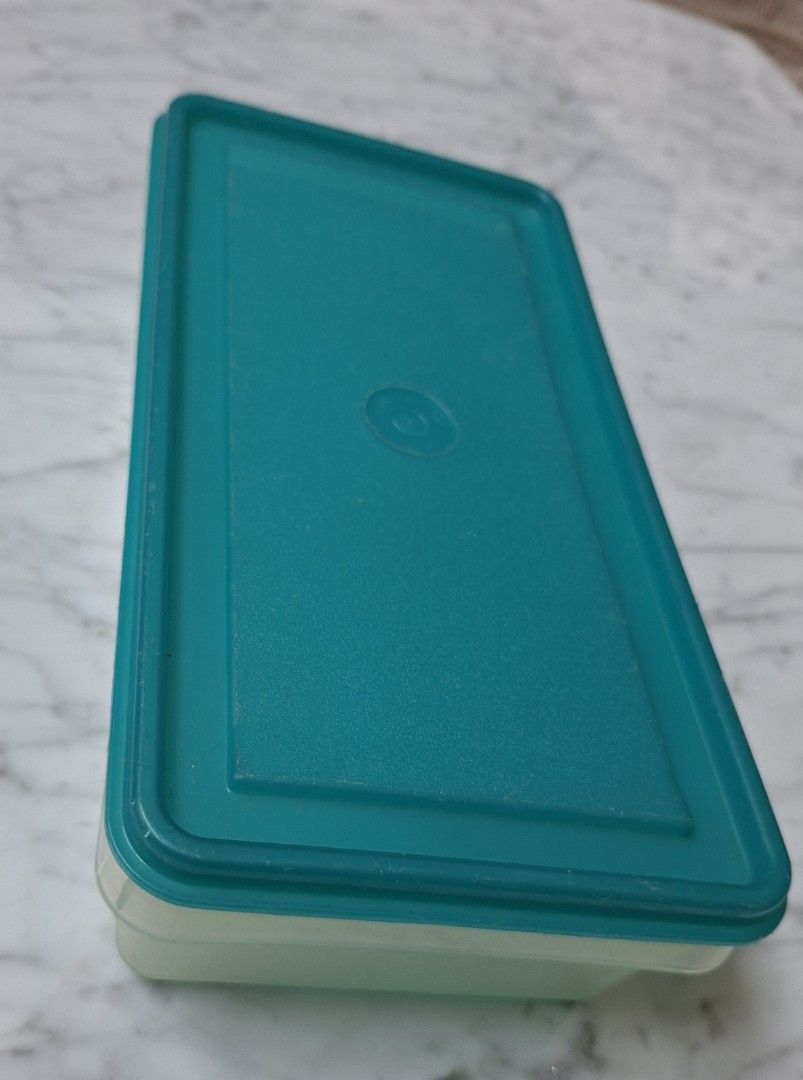Tupperware Rectangular Storage Container (Category: Food Organisation & Storage) located in Singapore. Submitted by ultimate1616 (Listing ID 1469603406, Image 2). Description: Rectangular storage container by Tupperware. Textured surface on the base panel with the Tupperware brand logo embossed on the bottom surface. Circular indentation in the center of the lid. Good size for organizing food or small household items. Dimensions: 26 cm (L) x 13 c