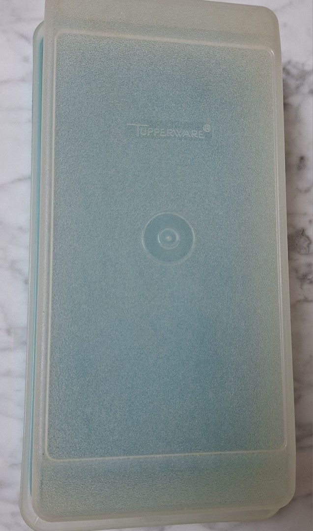 Tupperware Rectangular Storage Container (Category: Food Organisation & Storage) located in Singapore. Submitted by ultimate1616 (Listing ID 1469603406, Image 3). Description: Rectangular storage container by Tupperware. Textured surface on the base panel with the Tupperware brand logo embossed on the bottom surface. Circular indentation in the center of the lid. Good size for organizing food or small household items. Dimensions: 26 cm (L) x 13 c