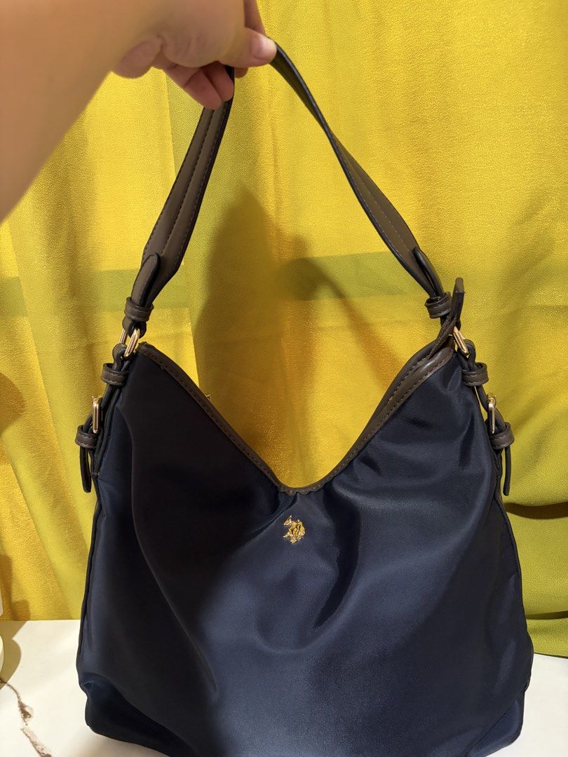 U.S. Polo Assn. Navigating Nylon Shoulder Bag (Category: Shoulder Bags) located in Borongan. Submitted by charmspreloveddd (Listing ID 1469638578, Image 2). Description: - Brand: U.S. Polo Assn. - Color: Navy blue with dark brown faux leather accents - Material: Durable nylon - Hardware: Gold-tone with branded logo and zipper pull - Closure: Zip-top for secure storage - Strap: Adjustable via side buckles - Condition: Clean condition with minor fl