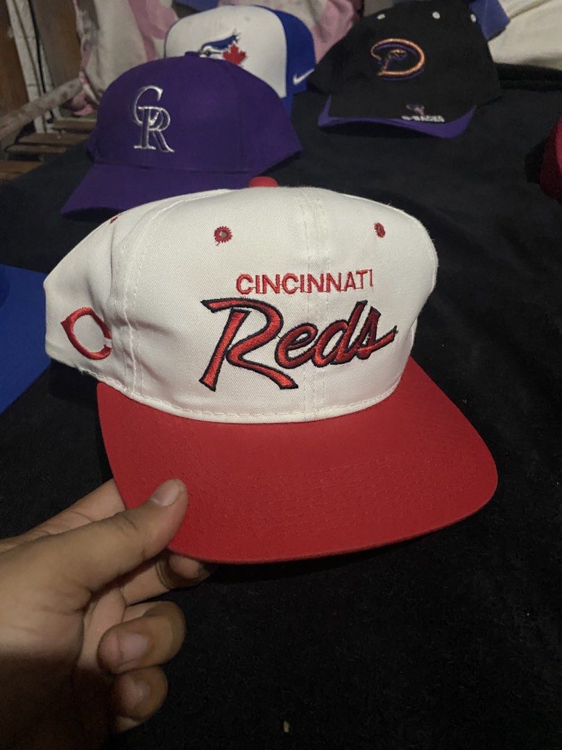 Vintage Cincinnati Reds Snapback Hat White Red (Category: Caps & Hats) located in Naga. Submitted by salakot4400 (Listing ID 1469742990, Image 1). Description: - Authentic vintage Cincinnati Reds snapback cap - Crisp white crown with bold red script embroidery - Matching red flat brim, top button, and side 'C' logo - Adjustable strap closure for a custom fit - Clean structure with vibrant colors, great for fans and collectors.