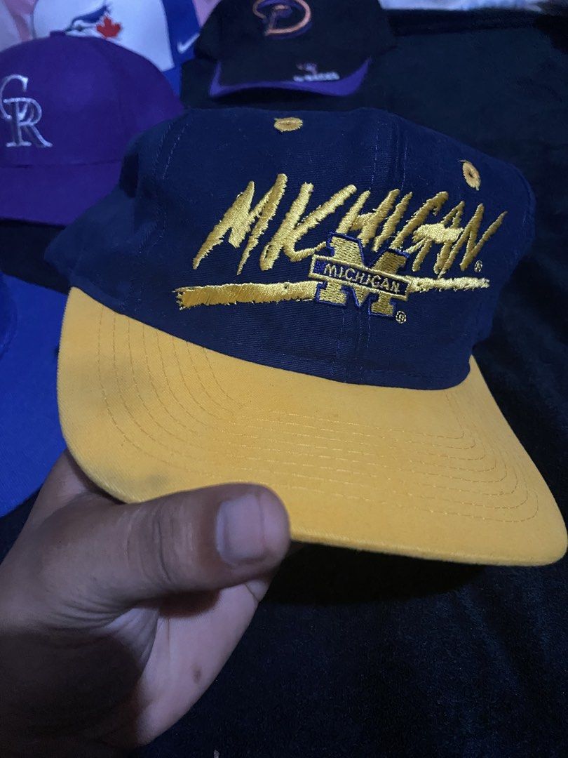 Vintage Michigan Wolverines Snapback Hat (Category: Caps & Hats) located in Naga. Submitted by salakot4400 (Listing ID 1469742881, Image 1). Description: - Color: Dark blue with classic yellow flat brim - Front: Yellow embroidered Michigan lettering - Back: Stitched Wolverines lettering across the arch and blue plastic adjustable snapback closure - Side: Signature branding on the lower panel - Condition: Brand new / Excellent quality - Perfect fo