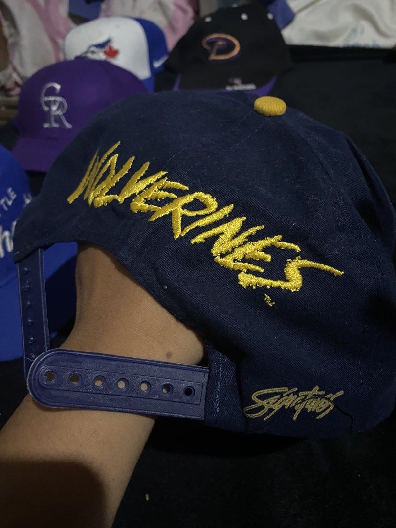 Vintage Michigan Wolverines Snapback Hat (Category: Caps & Hats) located in Naga. Submitted by salakot4400 (Listing ID 1469742881, Image 2). Description: - Color: Dark blue with classic yellow flat brim - Front: Yellow embroidered Michigan lettering - Back: Stitched Wolverines lettering across the arch and blue plastic adjustable snapback closure - Side: Signature branding on the lower panel - Condition: Brand new / Excellent quality - Perfect fo