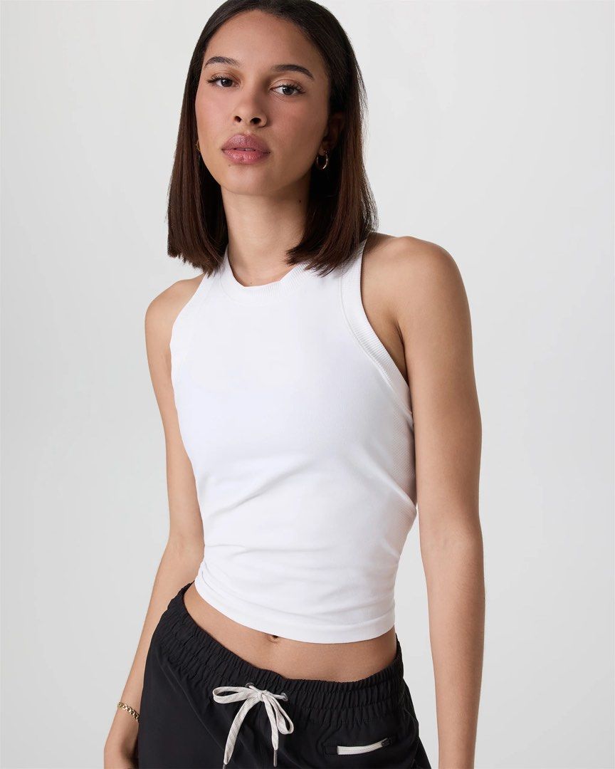 Vuori Seamless Tank (Category: Sleeveless) located in Makati City. Submitted by thevault88 (Listing ID 1469692377, Image 2). Description: - Brand: Vuori - Color: White - Style: Active seamless tank top with racerback - Features: Breathable perforated side panels and subtle embossed logo on the bottom left hem - Versatility: Ideal for workouts, gym sessions.