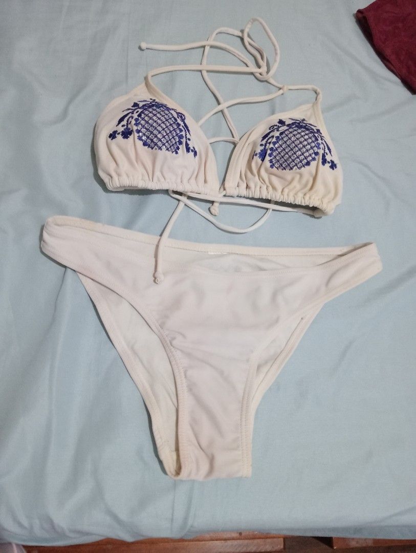 White bikini set with blue embroidered pineapple cups (Category: Bikinis & Swimsuits) located in Makati City. Submitted by YSL80022 (Listing ID 1469688976, Image 2). Description: - Color: White - Style: Two-piece bikini set - Top: Triangle design with blue embroidered pineapple details and small sparkly accents, featuring adjustable strappy tie closures - Bottoms: Matching solid white cheeky briefs - Condition: Clean fabric - Perfect for vacation