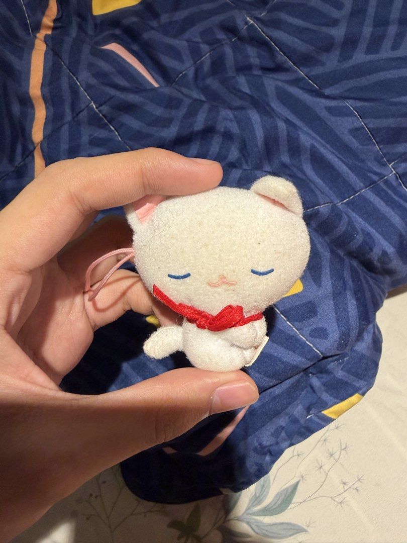 White cat plush keychain with red ribbon (Category: Plushies & Soft Toys) located in Makati City. Submitted by squishycorner (Listing ID 1469714286, Image 1). Description: - Adorable white cat plush keychain - Peaceful sleeping expression with charming blue stitched eyes - Festive bright red ribbon around the neck - Convenient pink string attached for easy hanging on bags or keys - Made with ultra-soft fabric material.