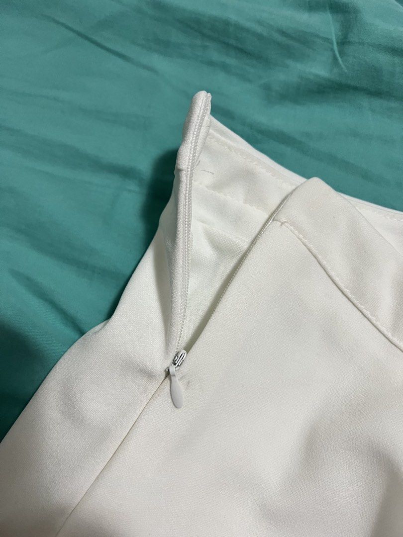 White mini skort with side zipper (Category: Skirts) located in Quezon City. Submitted by prelovedbykhy (Listing ID 1469747596, Image 3). Description: Solid white mini skort. Built-in shorts underneath for comfort and coverage. Asymmetrical front seam detail near the hem. Concealed side zipper closure. Smooth fabric with slight stretch. Clean and simple look, easy to pair with any top for casual outings..
